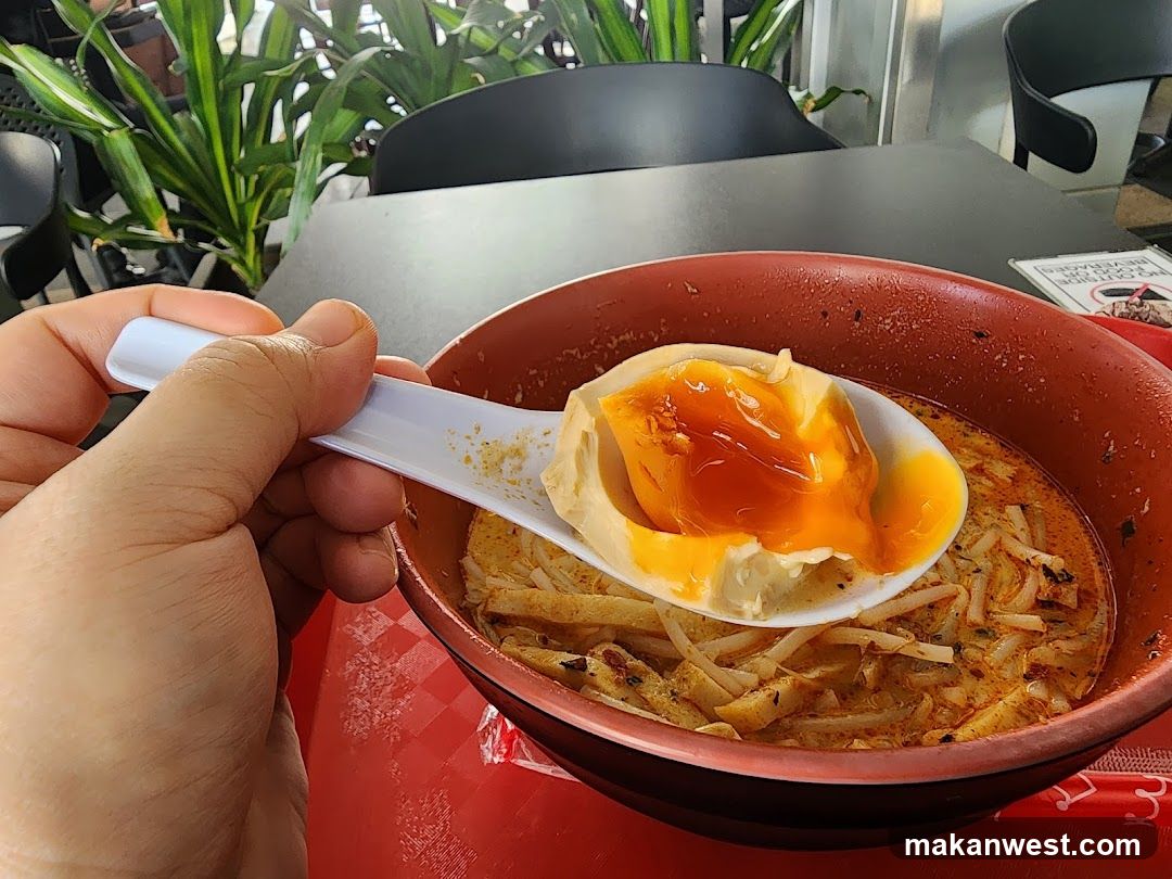 Close-up of a spoon with food over a bowl of noodles