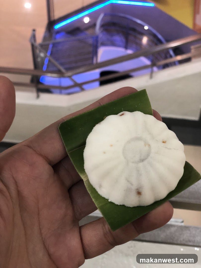 Hand holding a white pastry on banana leaf