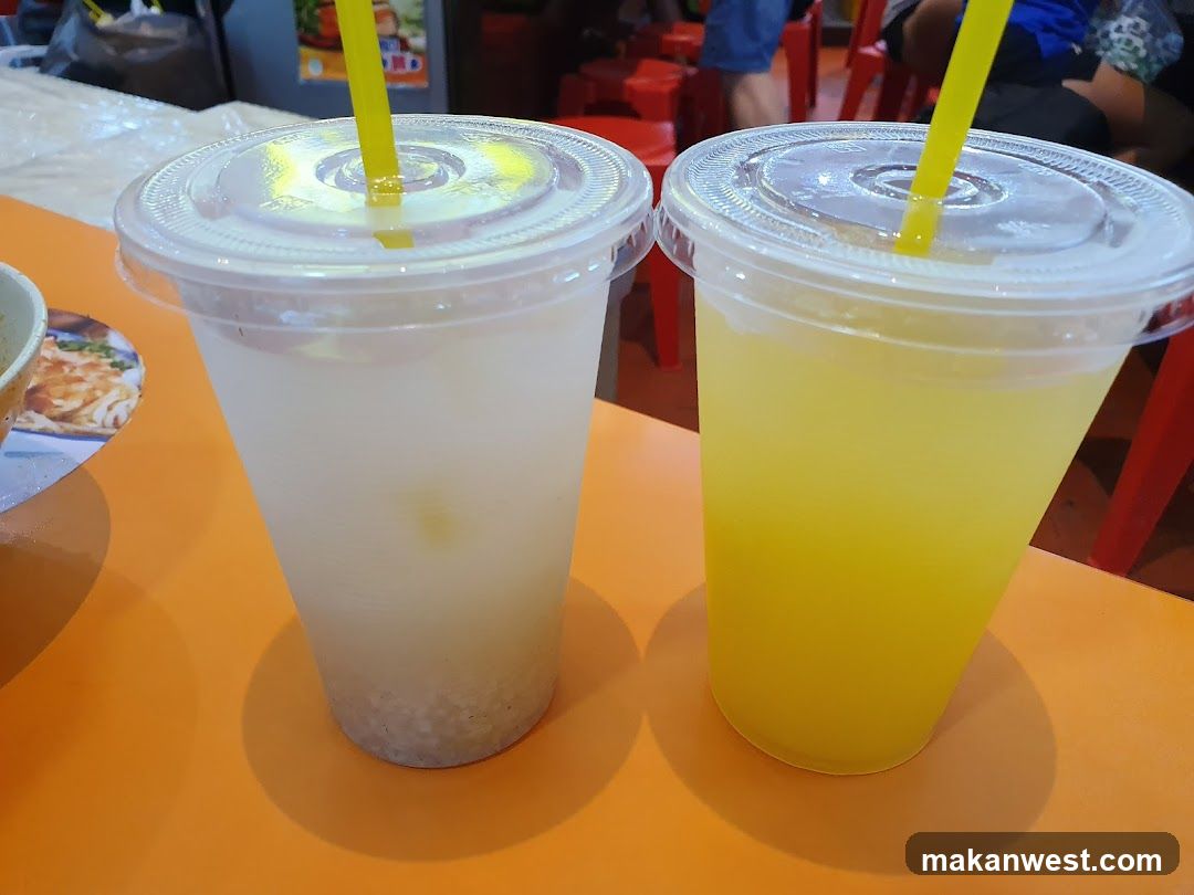 Two plastic cups with yellow straws on an orange table