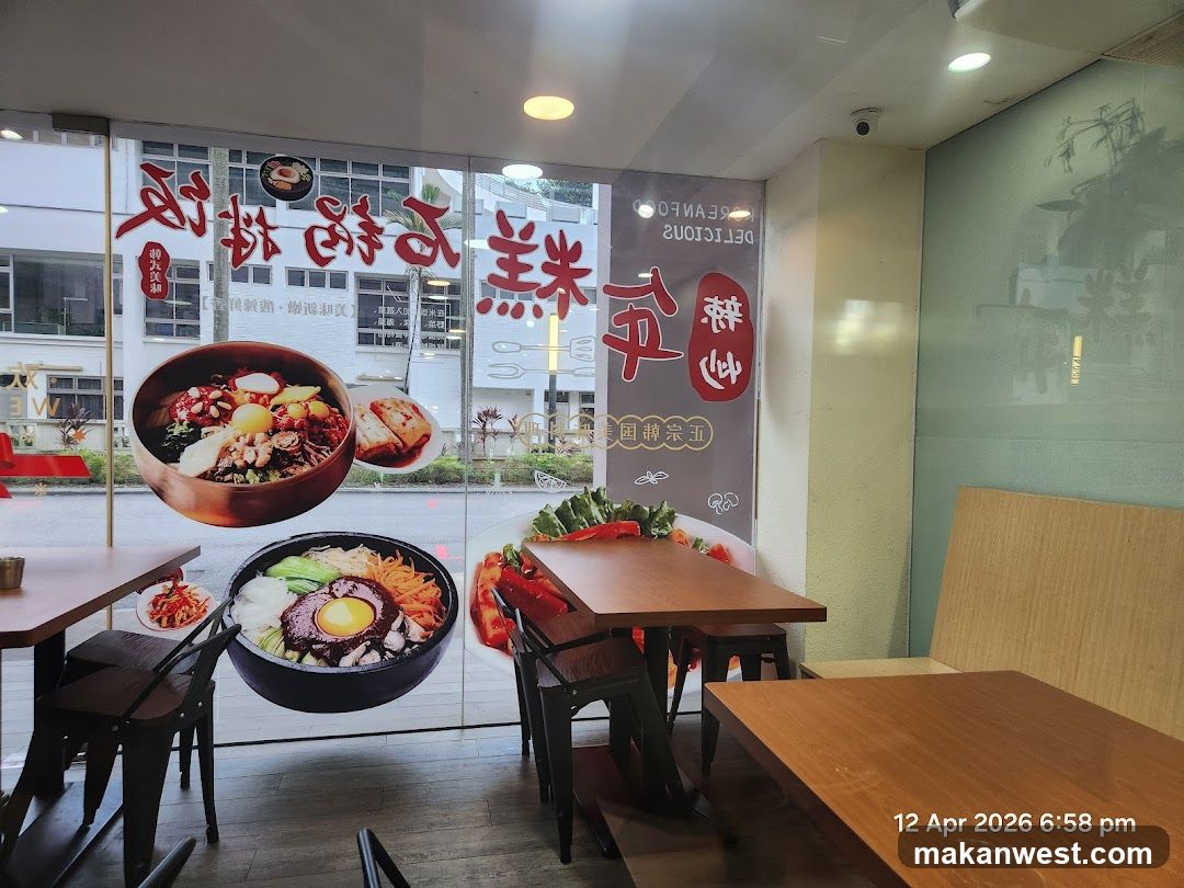 The image shows the interior of a Korean restaurant with a large window display featuring images of Korean food. The window has text in Chinese and English. Inside, there are tables and chairs.