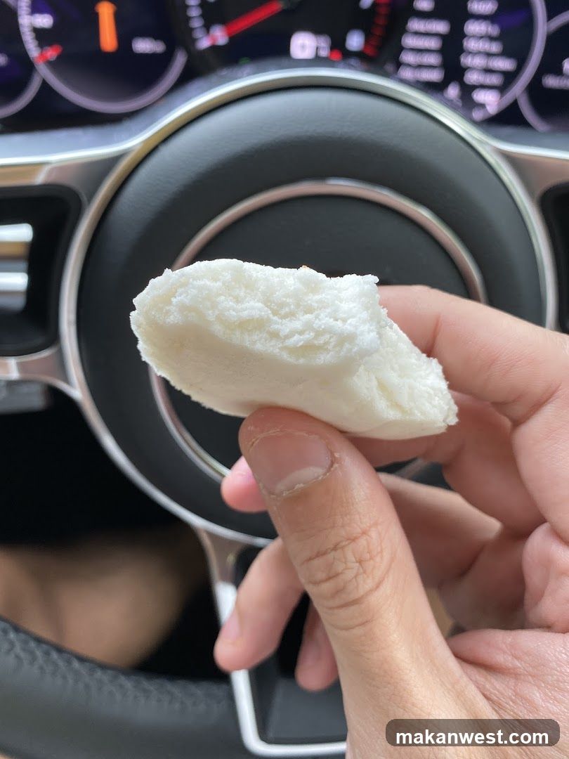 Hand holding a white pastry in a car