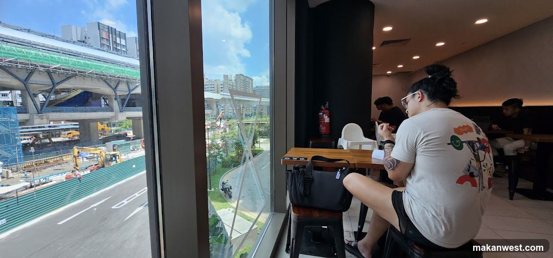 People sitting at tables inside a cafe with a view of construction outside