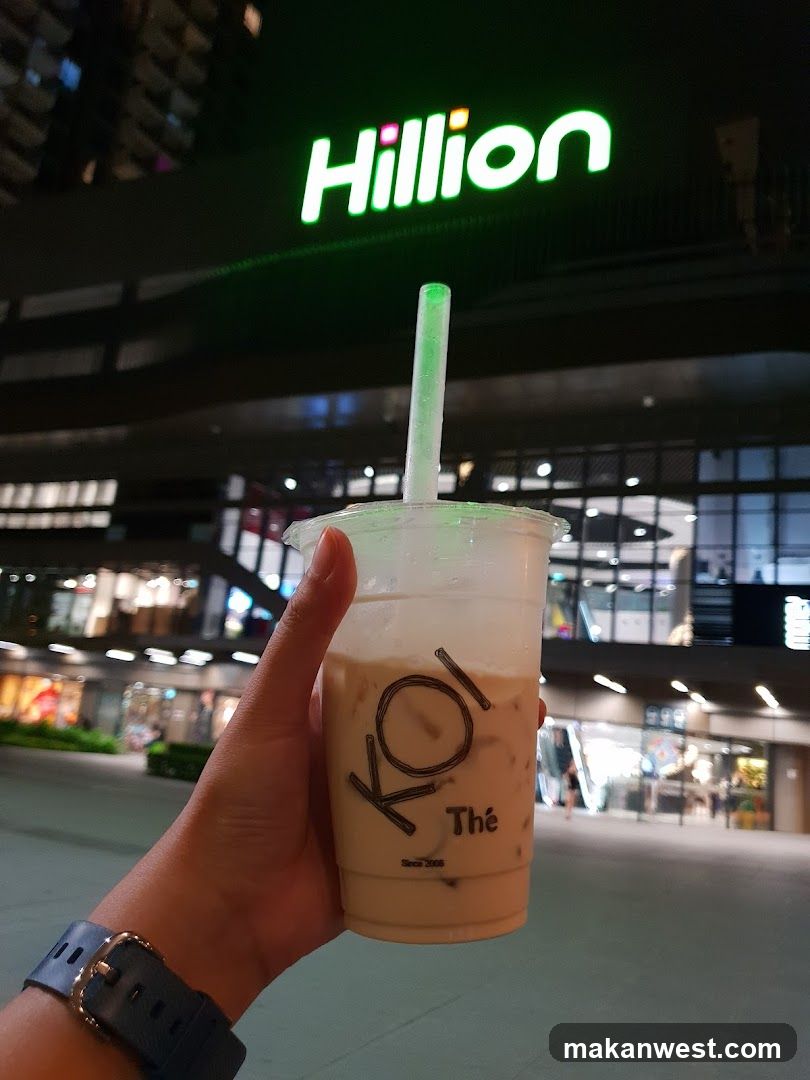 Person holding a drink in front of a building