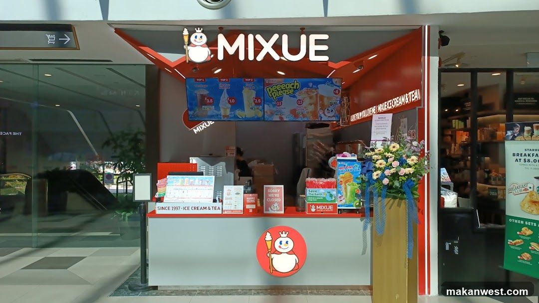 A Mixue ice cream and tea shop front with a prominent sign and menu boards. The shop has a red and white color scheme. There are several menu displays showing drinks and ice cream. A floral arrangement is placed to the right of the counter. A sign indicates the shop is closed.