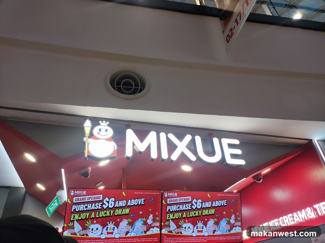A brightly lit storefront with the prominent "MIXUE" logo. Below the logo are two large digital screens advertising a grand opening promotion: "Purchase $6 and above, enjoy a lucky draw." The screens display cartoon characters and images of ice cream and drinks. A sign on the right side of the storefront reads "MIXUE ICE CREAM & TE".