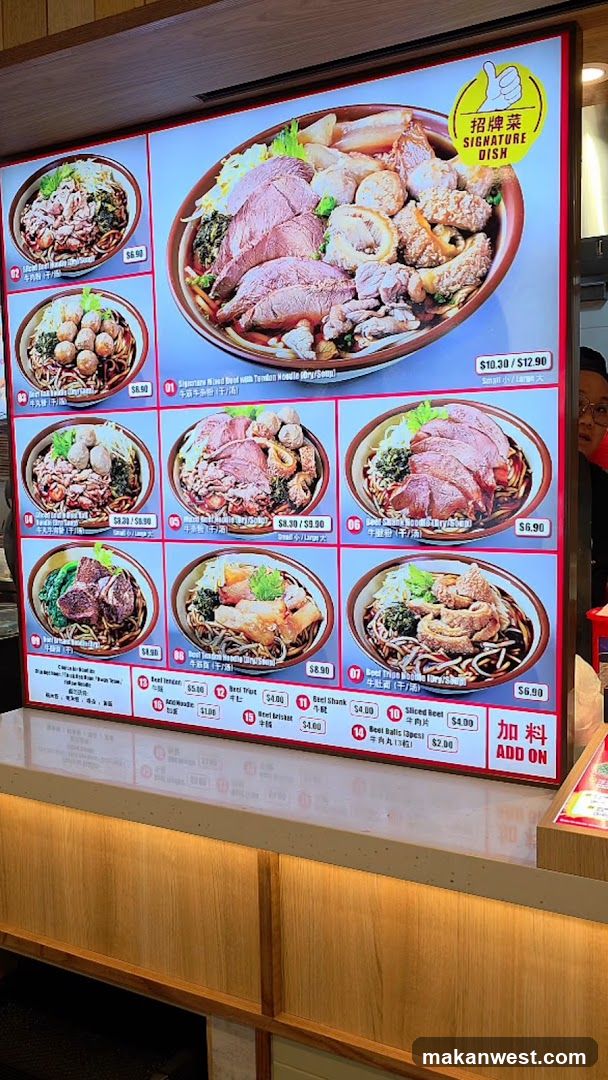 A digital menu board displaying various noodle dishes with beef and other ingredients. The main signature dish is prominently featured at the top.