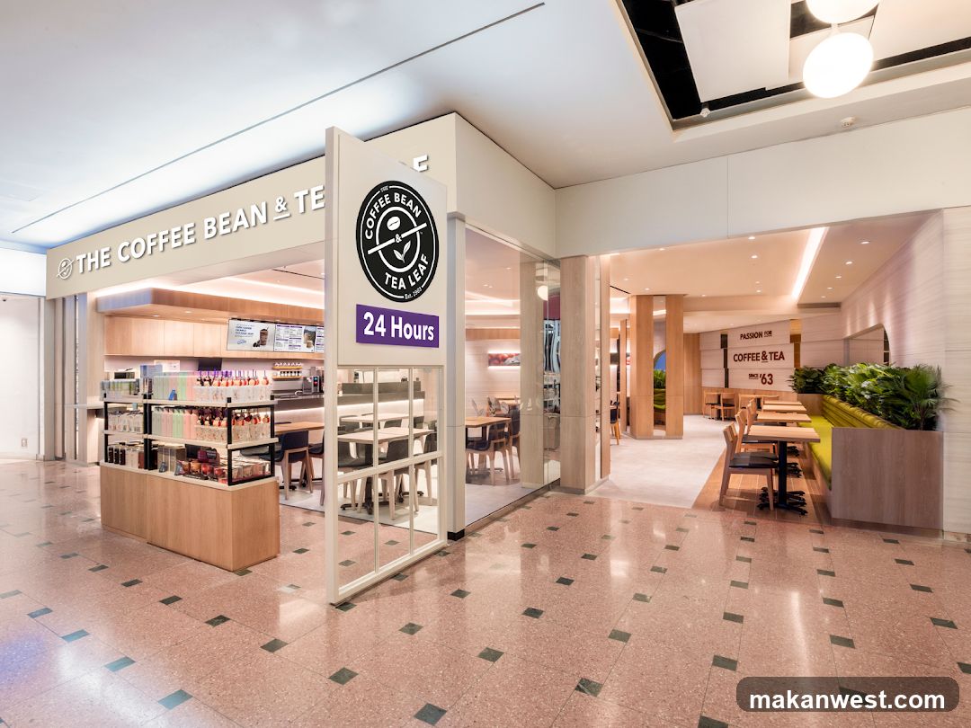 A brightly lit interior of a coffee shop with a clean, modern design. The storefront features large glass windows and a prominent sign that reads "THE COFFEE BEAN & TE" with the "TEA LEAF" logo. Inside, there are display shelves stocked with merchandise, a counter area, and seating arrangements. The shop is open 24 hours.