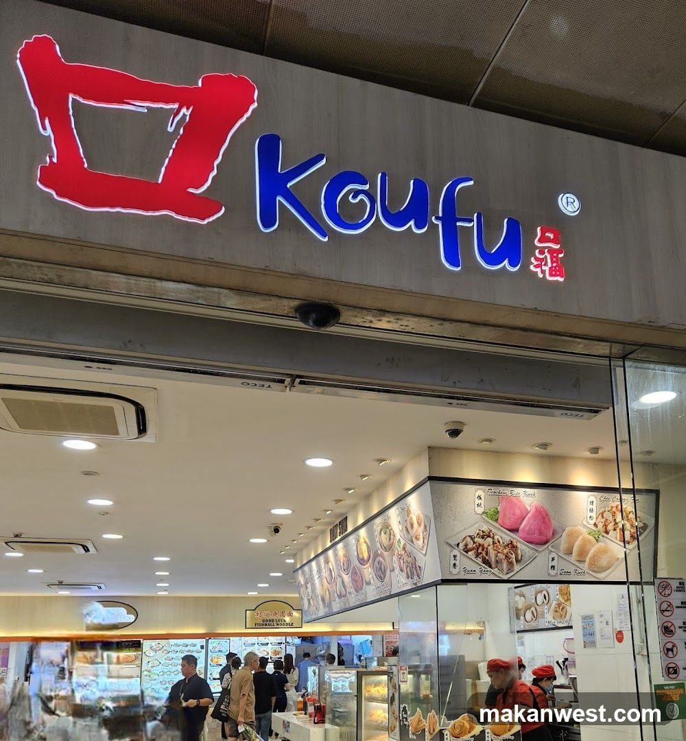 The exterior of a Koufu restaurant with a prominent sign above the entrance. Inside, customers are seen queuing and staff are preparing food. A large menu board displays various dishes.