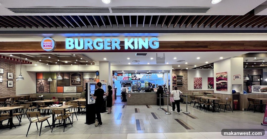 The exterior of a Burger King restaurant with its prominent signage and interior visible. The dining area with tables and chairs is set up, and customers are seen ordering at the counter.