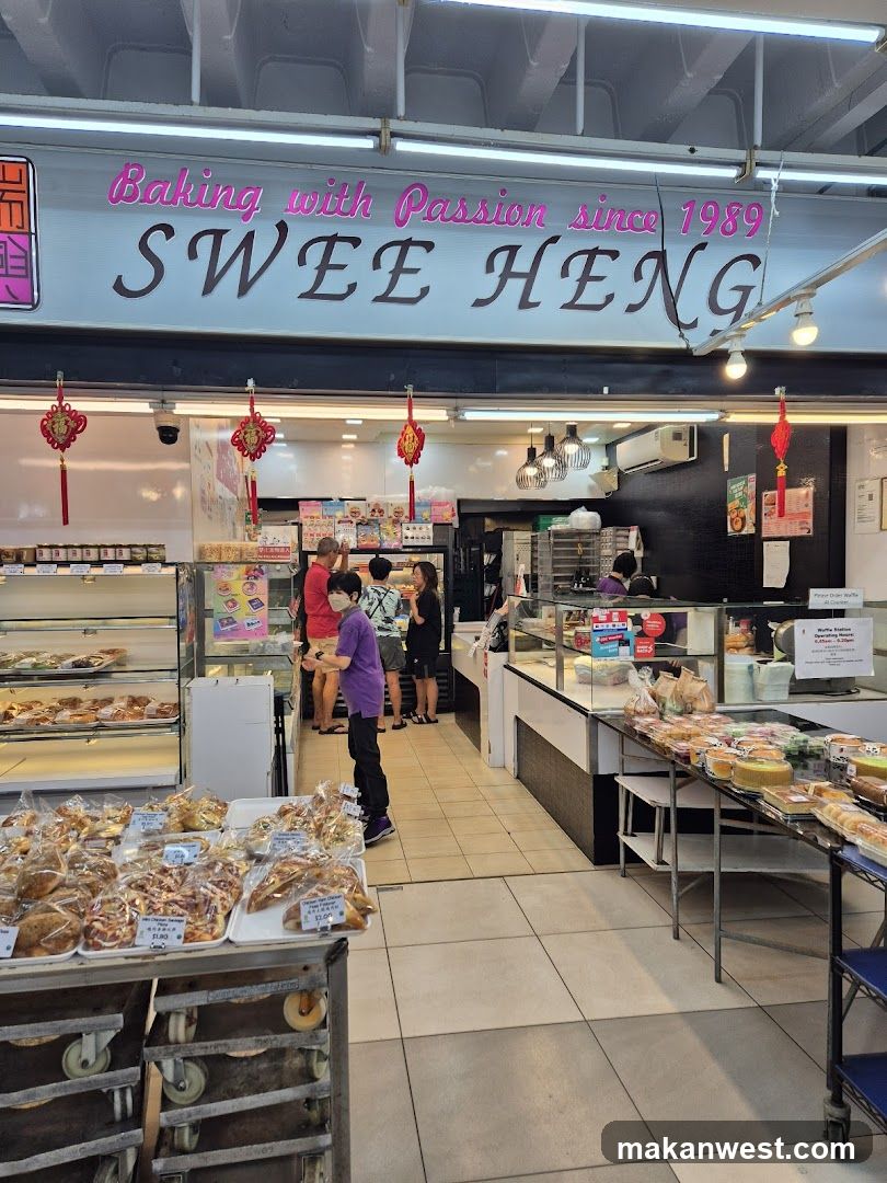 The exterior of a bakery with a prominent sign that reads "Baking with Passion since 1989 SWE HENG". Inside, various baked goods are displayed on shelves and in display cases. Customers are seen browsing and purchasing items. Red Chinese knots hang as decorations.