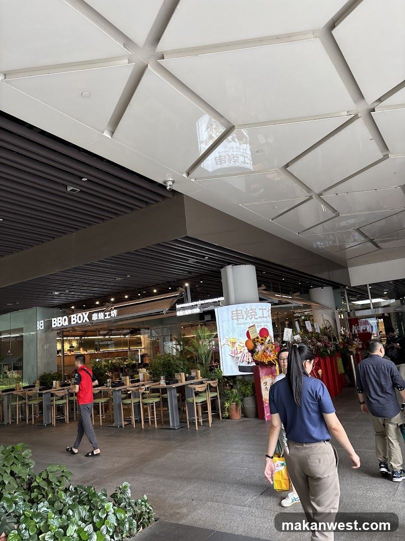 The exterior of a BBQ restaurant with tables and chairs set up outside. The sign above the entrance reads "BBQ BOX" and Chinese characters.