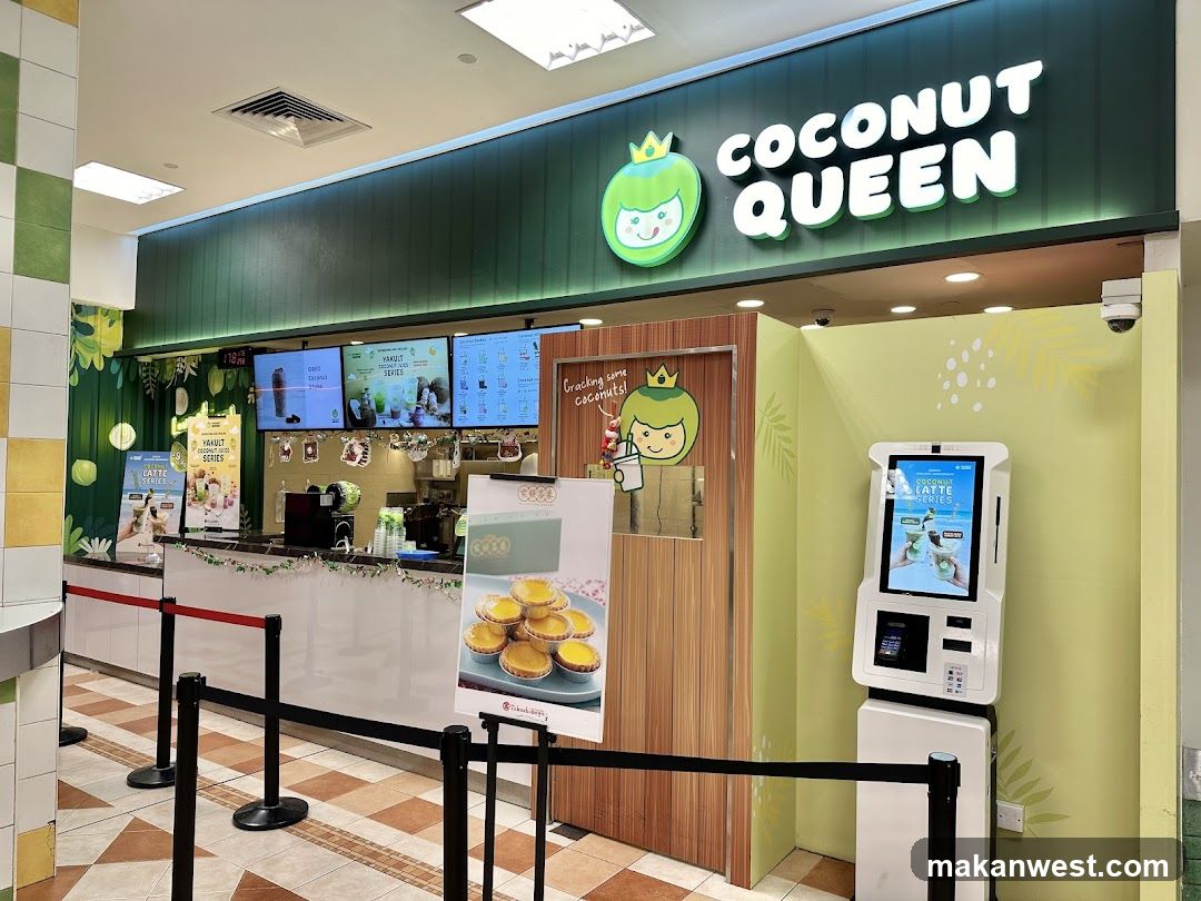 The exterior of a Coconut Queen shop with a prominent sign above the counter. Digital menu boards display various drinks and promotions. A self-order kiosk is visible to the right. The counter area is decorated with festive garlands.