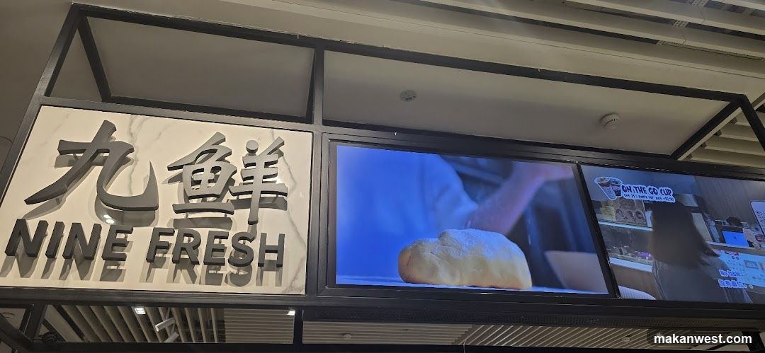 The image shows the storefront of a shop named 'Nine Fresh' (九鲜). The sign features large Chinese characters and English text below them. To the right, there are digital screens displaying food items like bread and beverages.