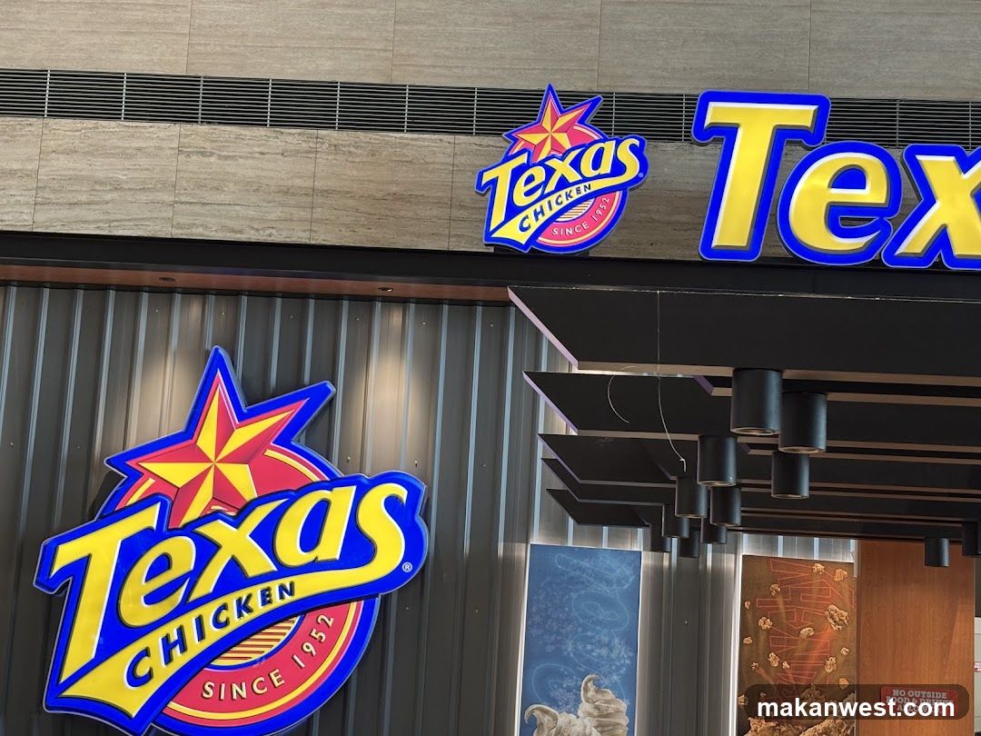 Photo of physical exterior entrance/storefront facade with visible signage ON the building. Large Texas Chicken logo on wall and smaller sign above entrance.