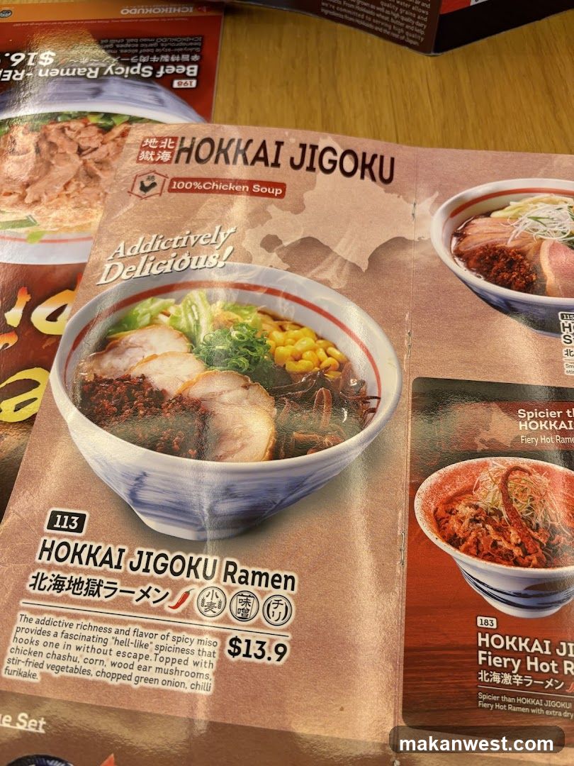 A close-up of a printed menu page featuring Hokkai Jigoku Ramen with spicy miso broth, topped with pork slices and corn. The dish is priced at $13.9. Adjacent items include Fiery Hot Ramen and Beef Spicy Ramen. Background shows partial views of other menu pages.