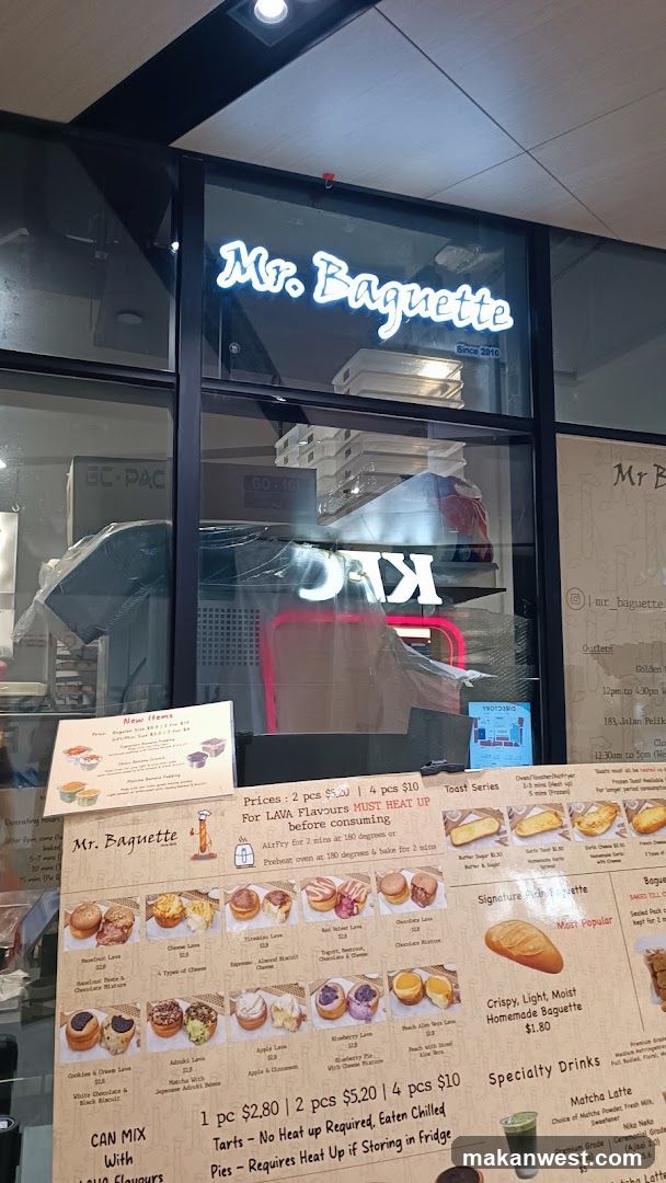 A storefront with a neon 'Mr. Baguette' sign above the entrance. Inside, KFC branding is visible on equipment. A large menu board displays various pastries and drinks with prices.