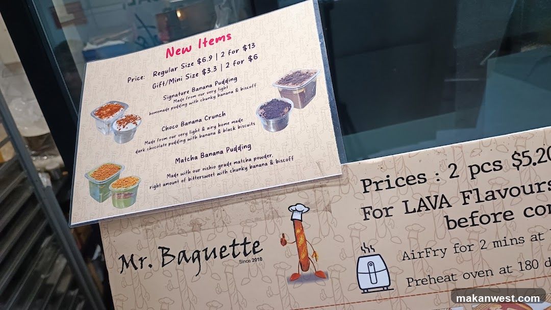 A close-up of a printed menu board displaying new dessert items with prices and descriptions, placed on a glass surface near a shop entrance.