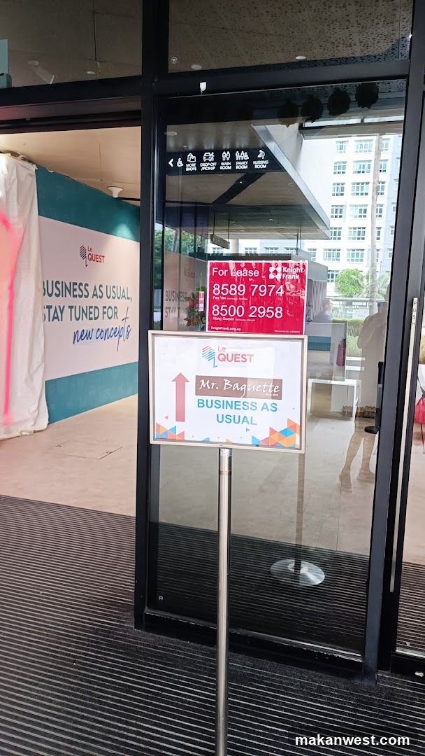 Photo of the exterior entrance to Le Quest, a commercial space in Singapore. Visible signs include 'For lease' contact numbers and a 'Business as Usual' notice for Mr. Baguette. A banner inside reads 'Stay tuned for new concepts'. The building facade includes glass doors and signage indicating multiple units.