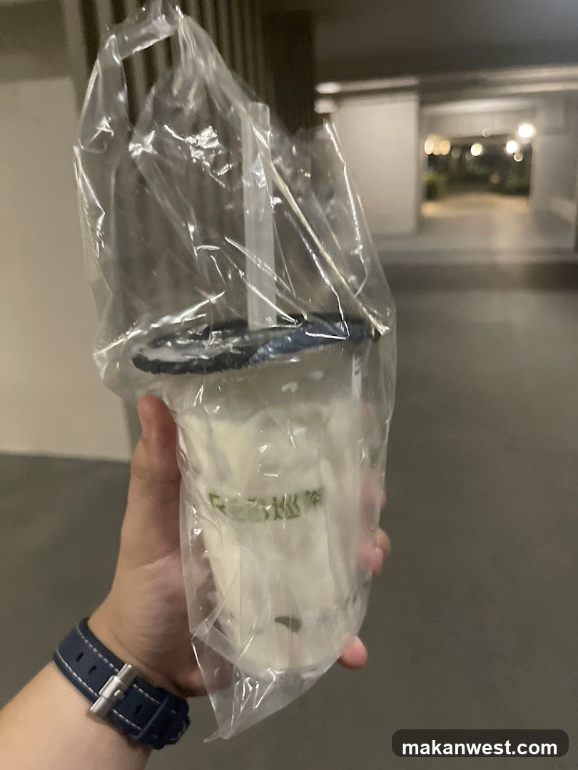 Hand holding a plastic-wrapped drink