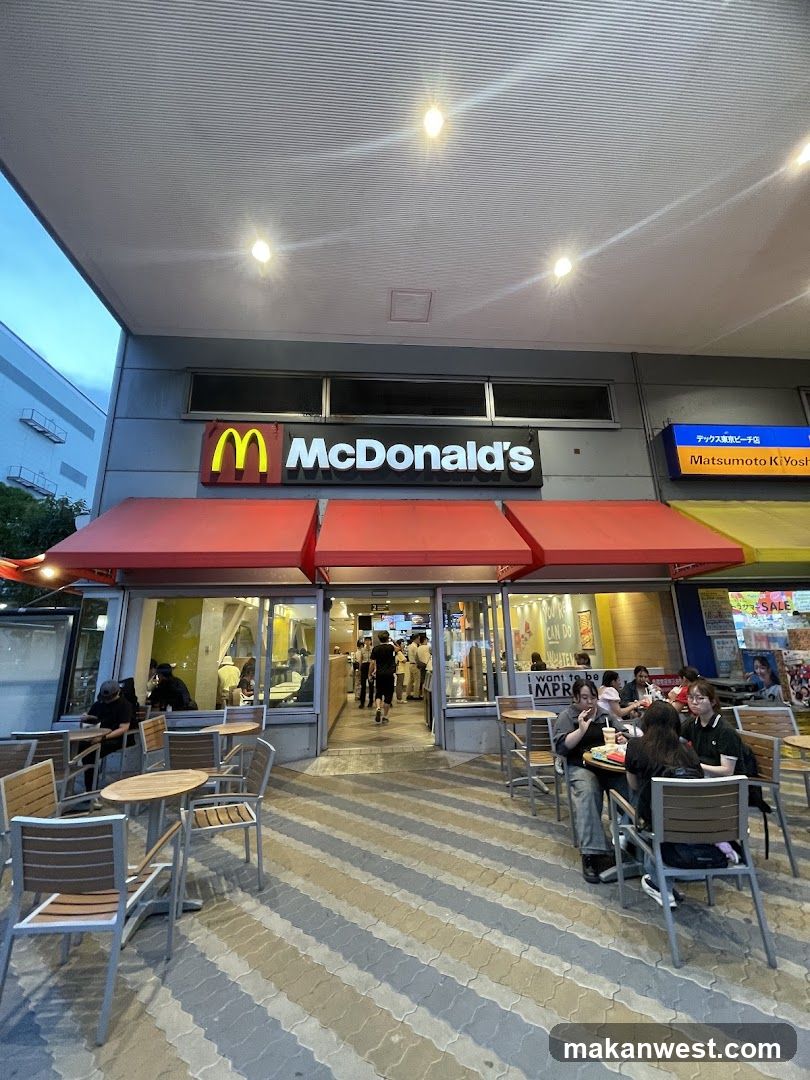 Photo of McDonald's physical entrance with visible signage, red awnings, and outdoor seating area.