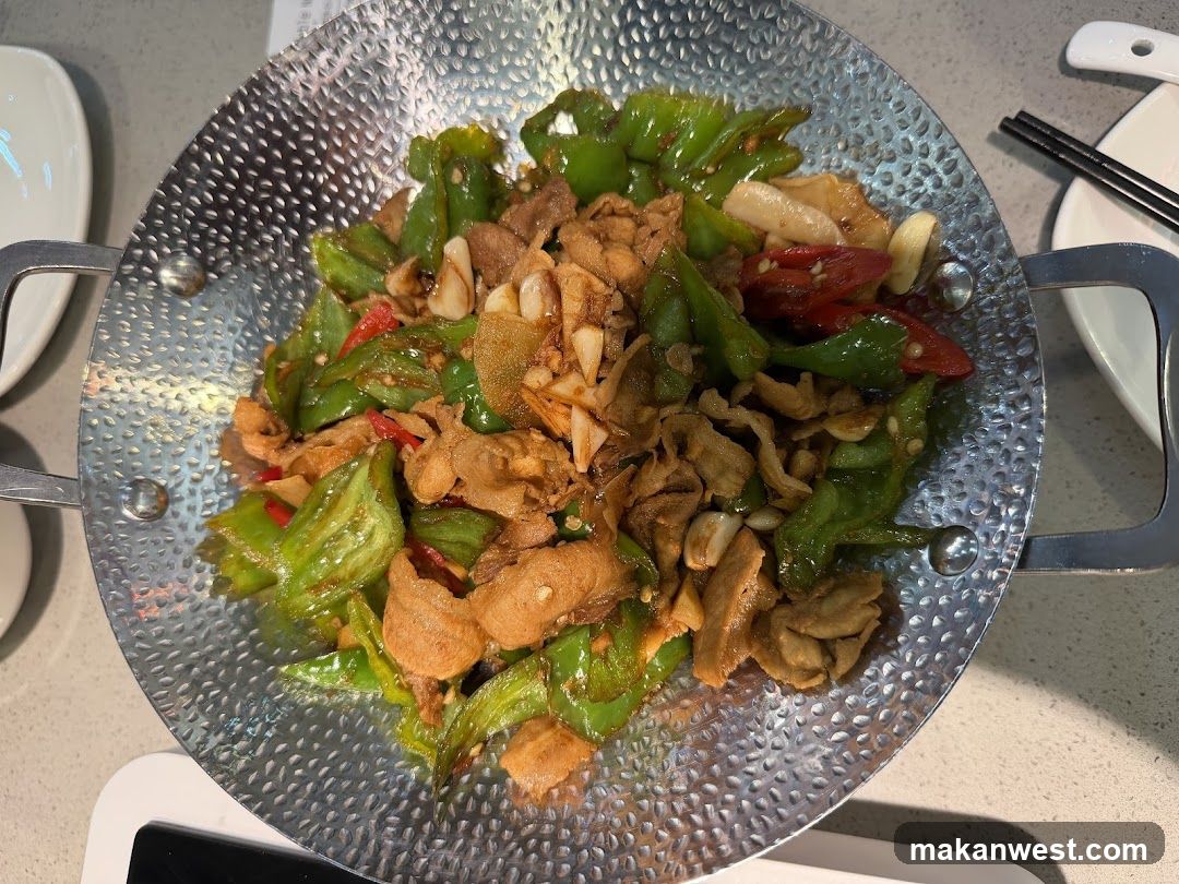 Stir-fried meat with peppers in a hammered metal pan
