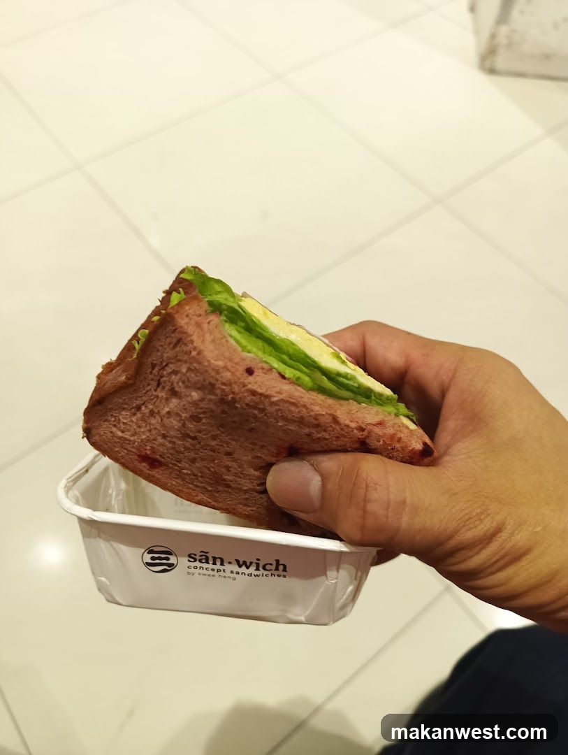 Hand holding sandwich in branded container
