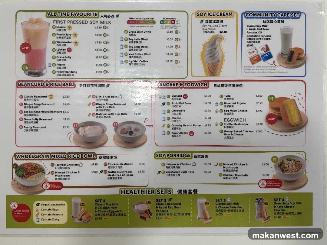 A printed menu board featuring sections like 'All Time Favourite', 'Beancurd & Rice Ball', 'AnCake & Eggwich', and 'Healthier Sets'. It lists various soy milk drinks, rice balls, pancakes, eggwiches, and healthier meal sets with prices.
