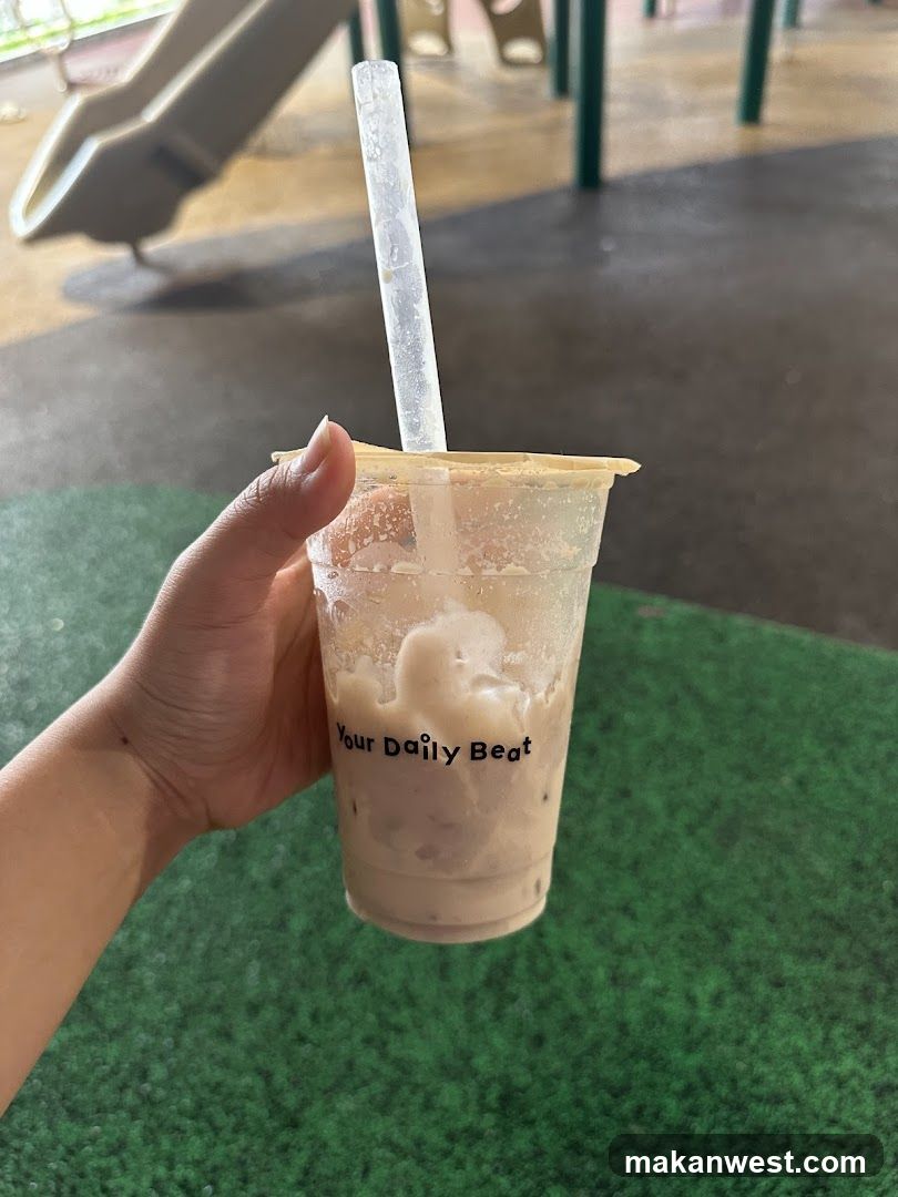 Hand holding iced beverage at playground