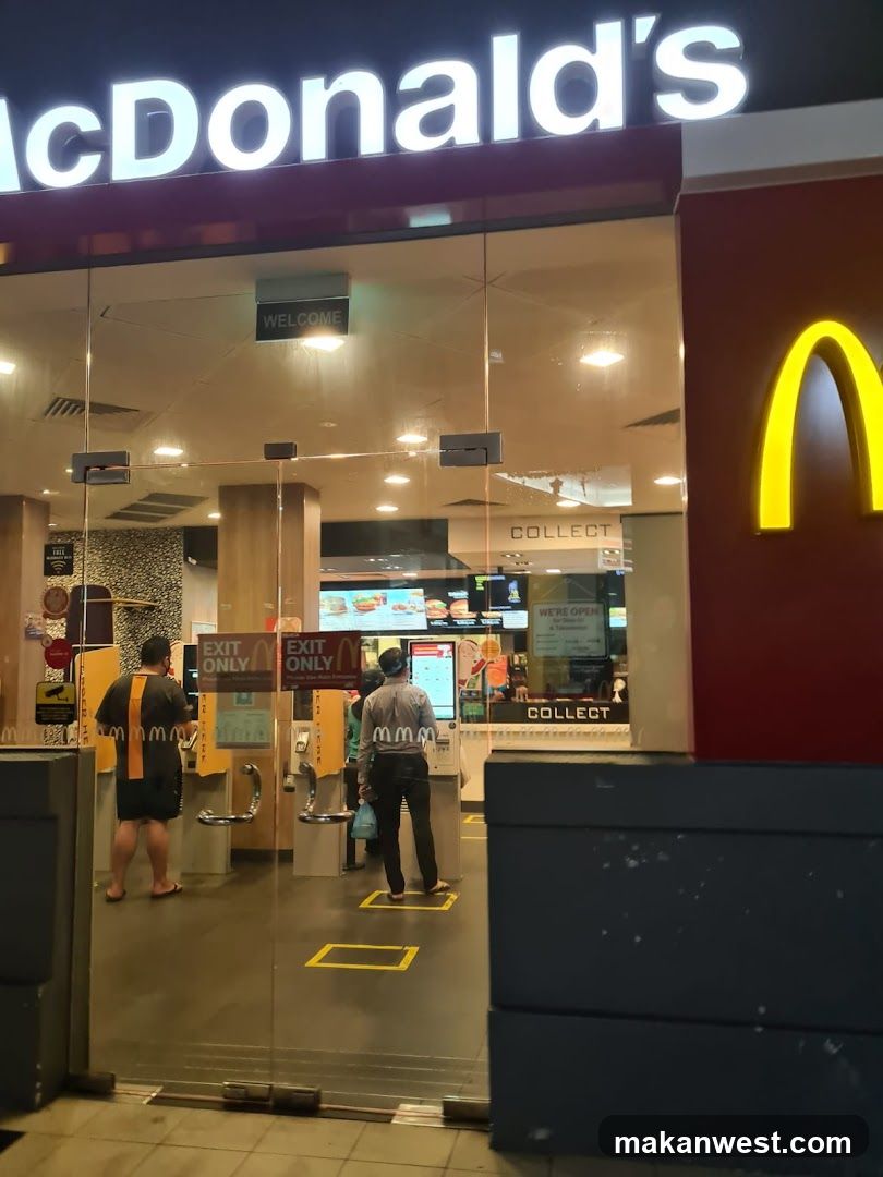 Photo of the physical exterior entrance of a McDonald's restaurant, showing illuminated signage and glass doors with customers inside.