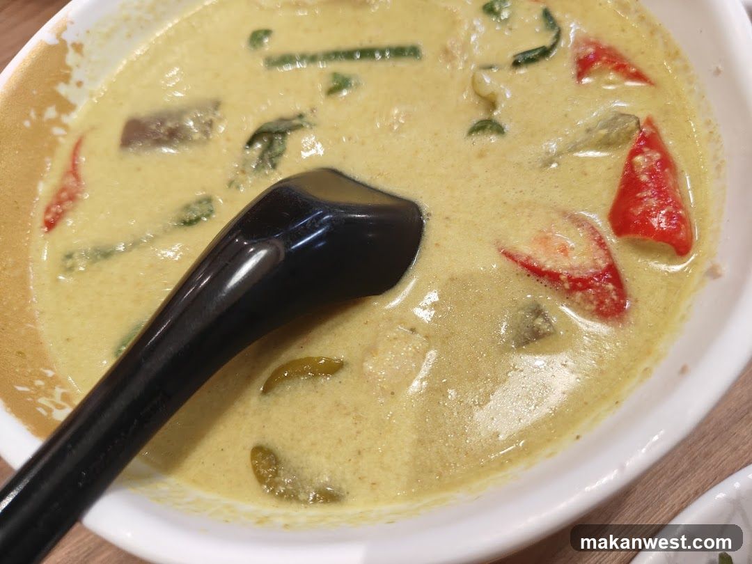 Bowl of creamy curry soup with vegetables and a black spoon