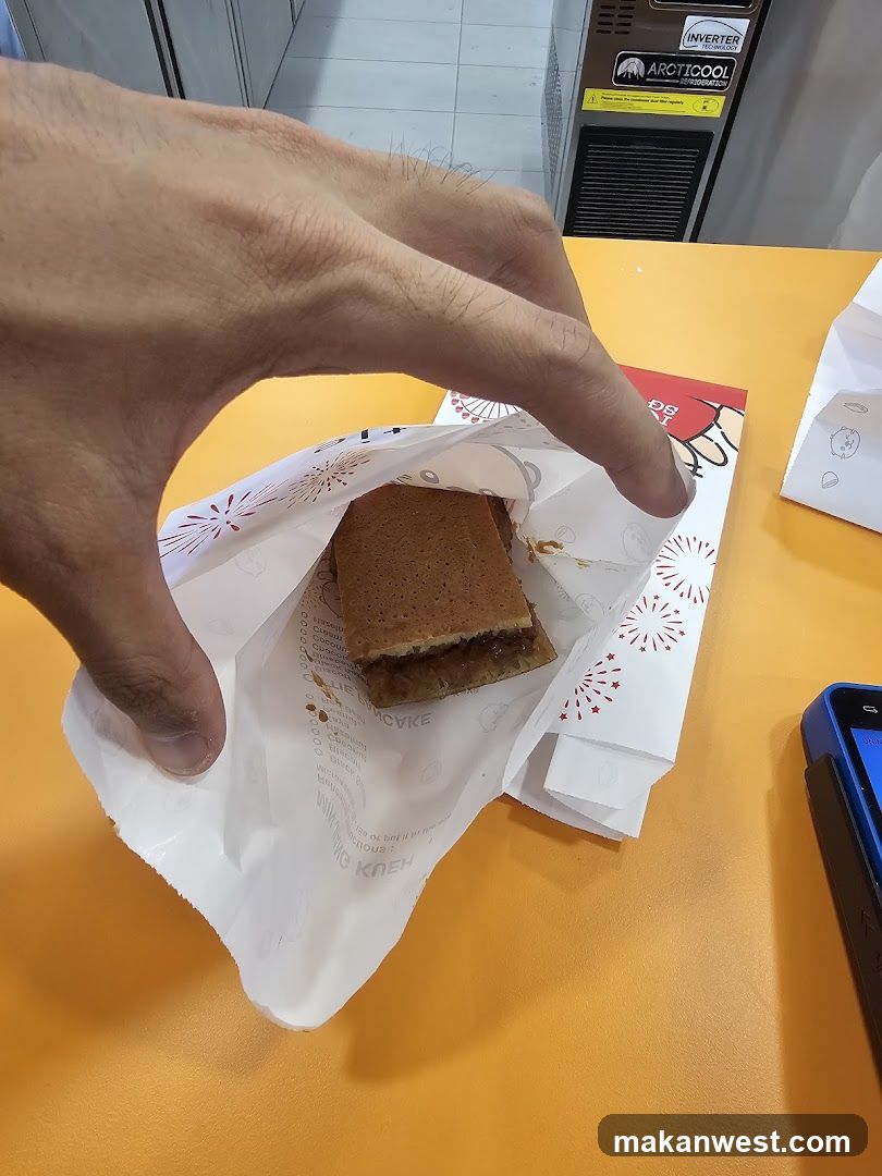 Hand holding a pastry in a paper bag