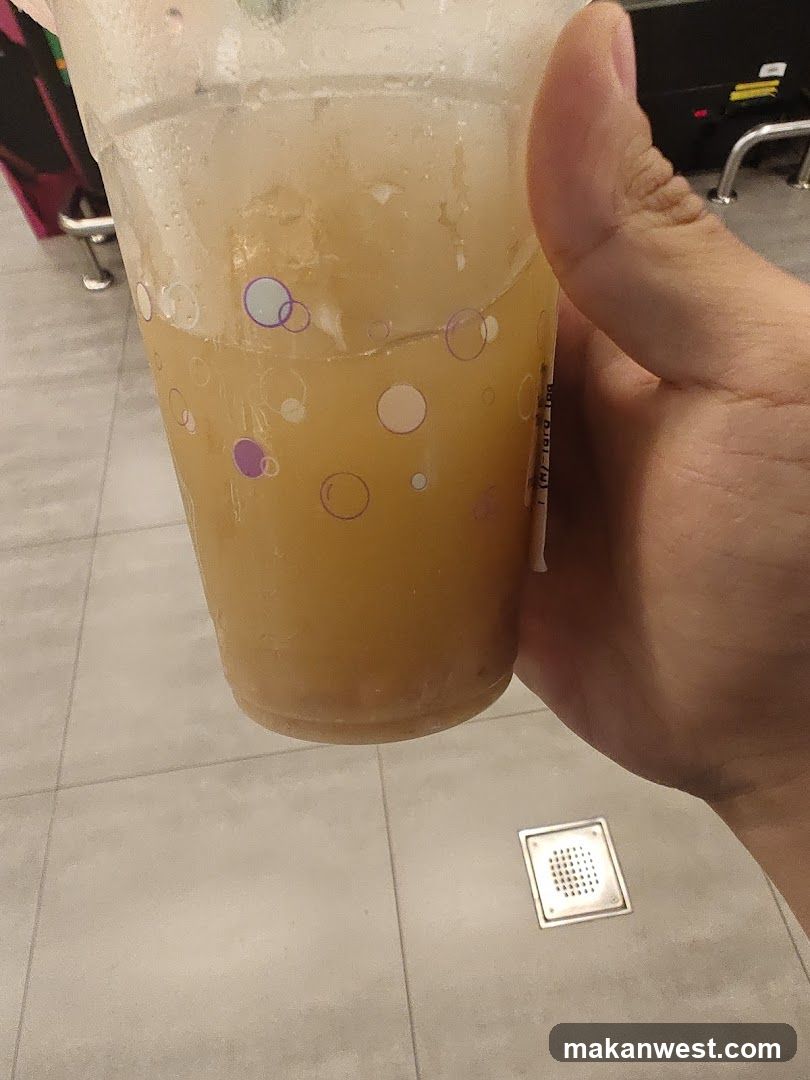 Hand holding a plastic cup with yellowish drink