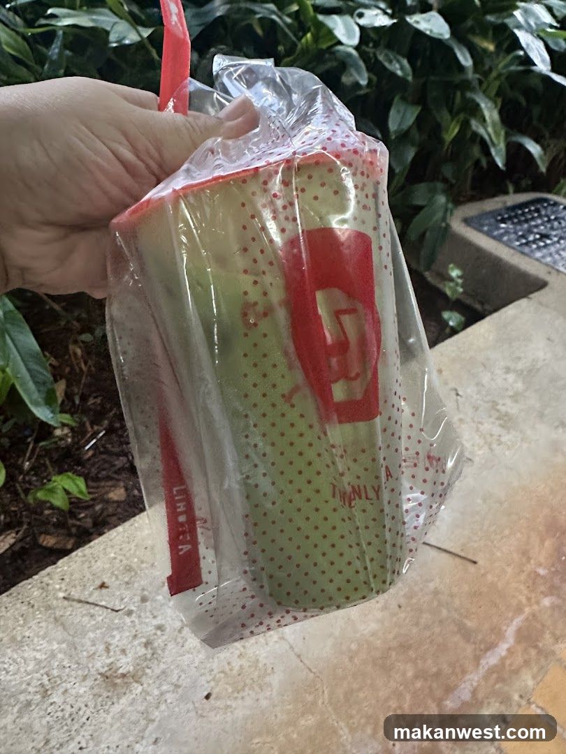 Hand holding a plastic-wrapped drink cup