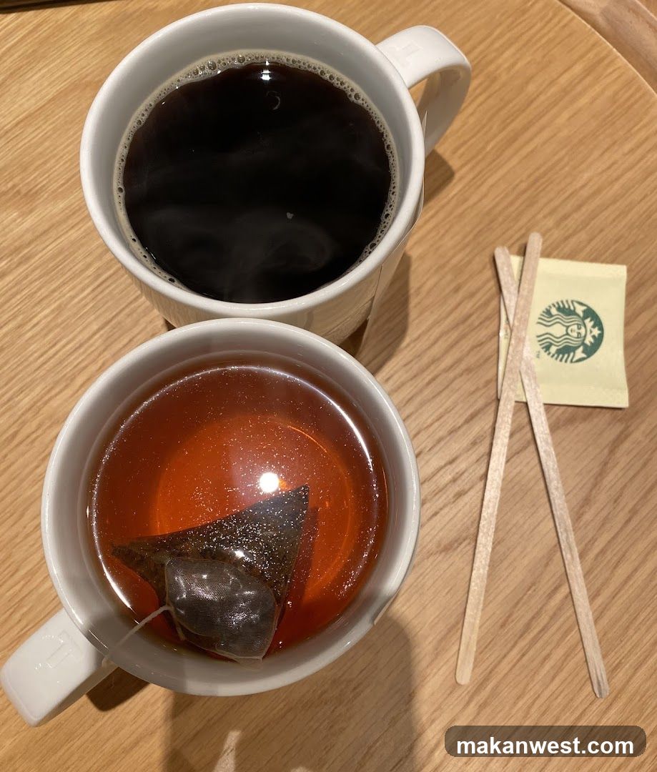 Two cups of tea and coffee with stirrers