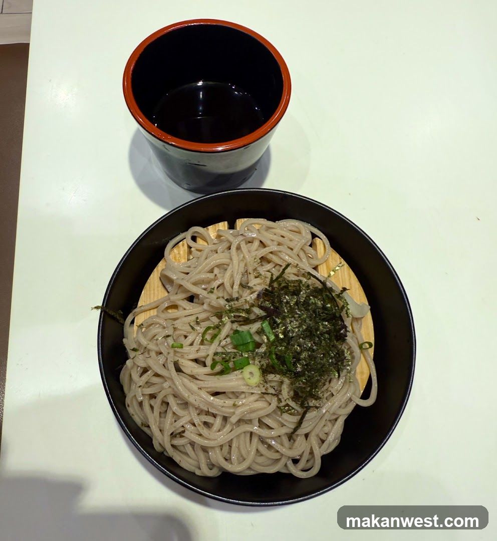 Bowl of noodles with toppings and a cup of dark liquid