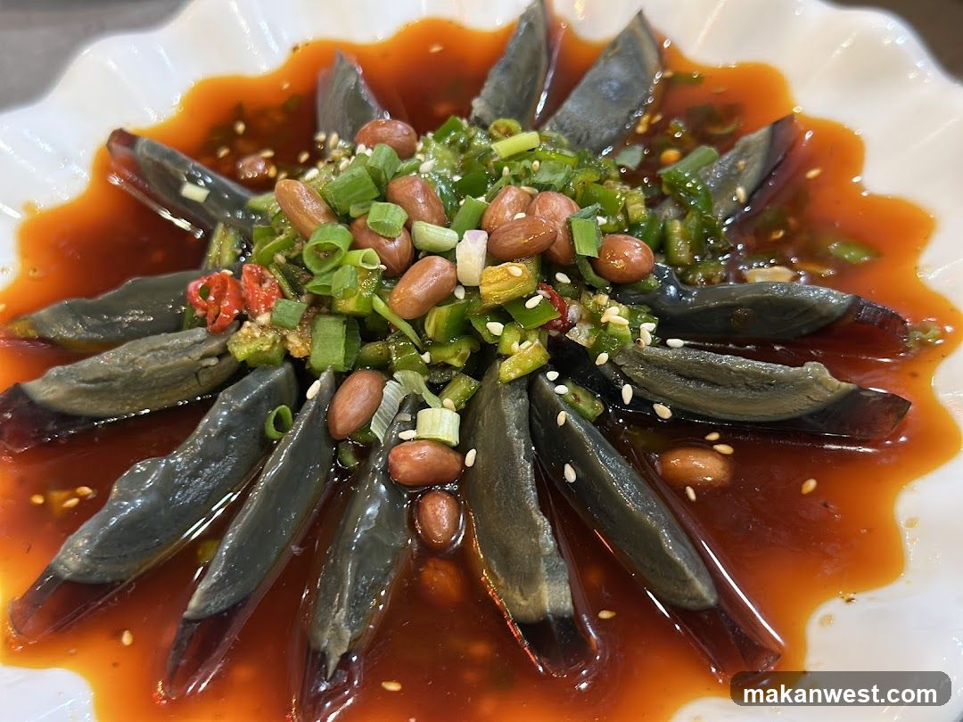 Dish with dark jelly-like slices in red sauce, garnished with green onions and peanuts