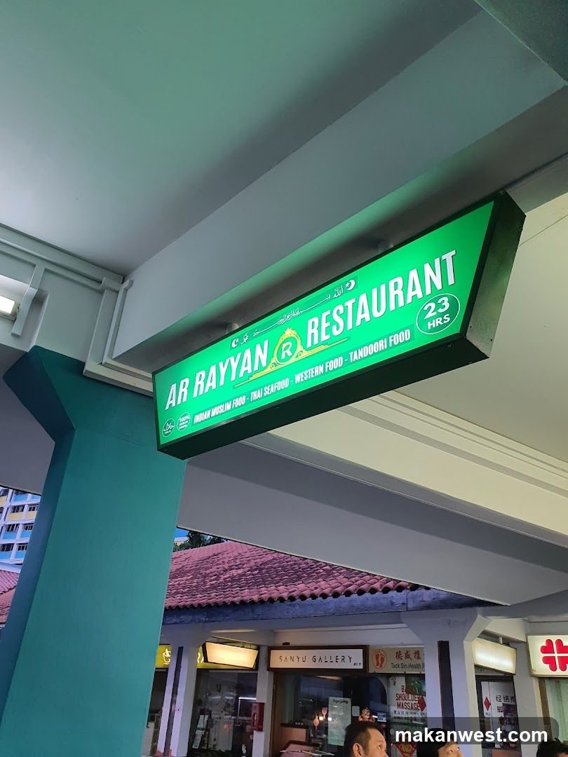 A green illuminated signboard mounted above a storefront entrance, displaying 'AR RAYAN RESTAURANT' with categories including Indian Muslim Food, Thai Seafood, Western Food, and Tandoori Food. The building features teal pillars and a tiled roof visible below the sign.
