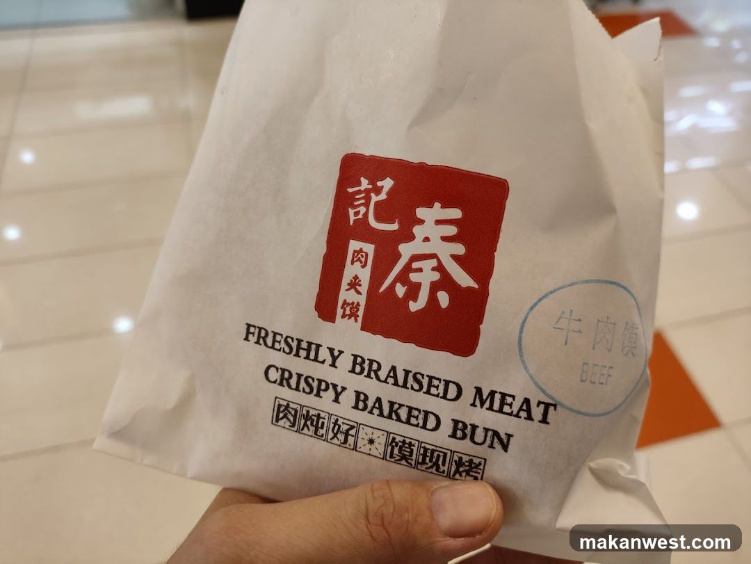 A hand holding a white paper bag with Chinese and English text.