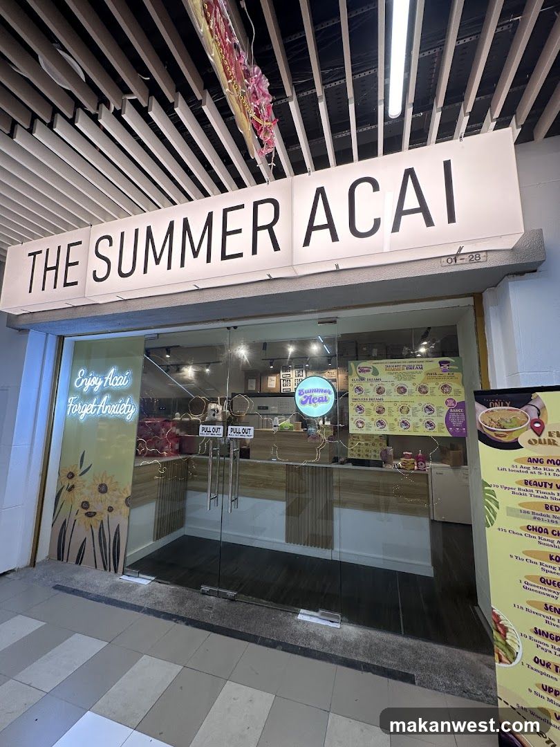 A modern storefront with a large white sign reading 'THE SUMMER ACAI' above glass doors. Inside, neon signs and menu boards are visible on the walls.