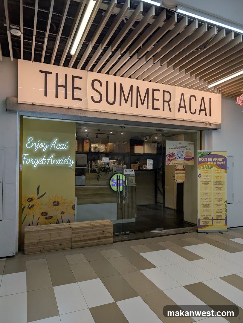 A modern storefront with a large sign reading 'THE SUMMER ACAI'. The entrance features glass doors and a wooden bench outside. Neon signs on the left say 'Enjoy Acai, Forget Anxiety' with sunflower illustrations. Inside, shelves display products. To the right, a menu board lists various acai bowls and drinks.