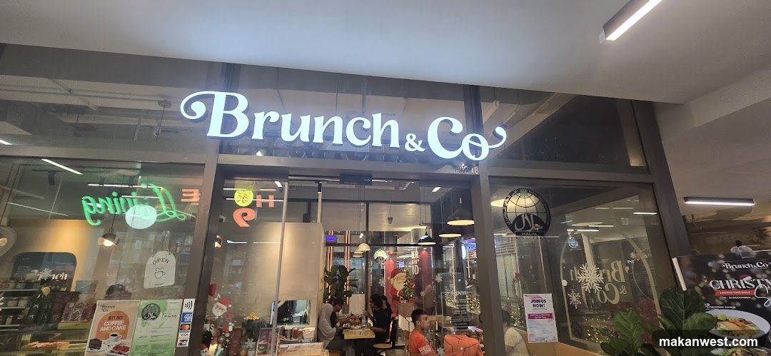 A modern storefront with illuminated signage reading 'Brunch & Co' above glass doors and windows. Inside, patrons are seated at tables under pendant lights. Decorative elements include Christmas ornaments and a snowflake design on the window. Posters and flyers are visible near the entrance.