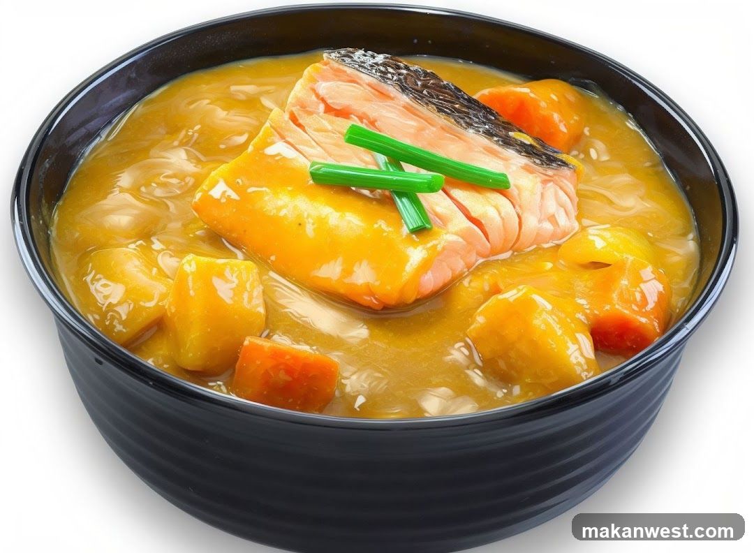 A close-up shot of a black bowl filled with a rich, yellow curry sauce. The curry contains chunks of vegetables, possibly potatoes and carrots, and is topped with a generous piece of salmon fillet. The salmon has crispy skin and is garnished with chopped green onions. The dish is presented against a white background.